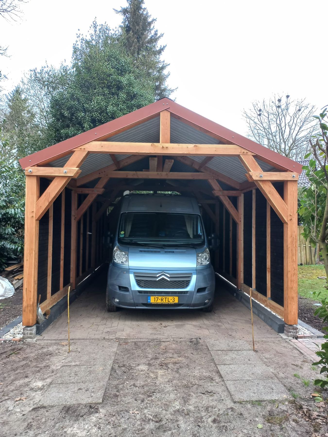 Bestelbus onder een carport met zadeldak en open voorzijde