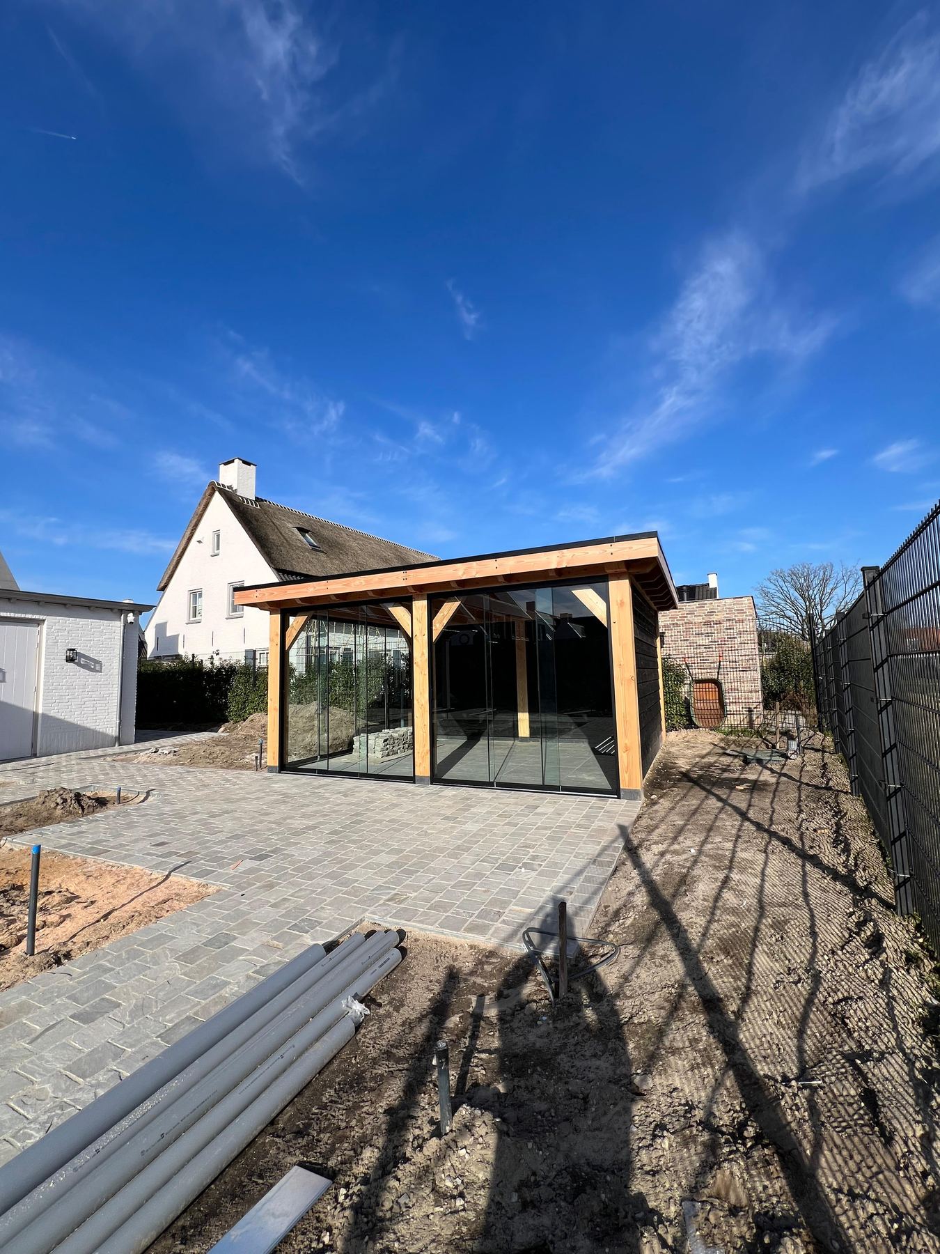 Tuinkamer met glazen schuifwanden en een douglas constructie onder een blauwe lucht