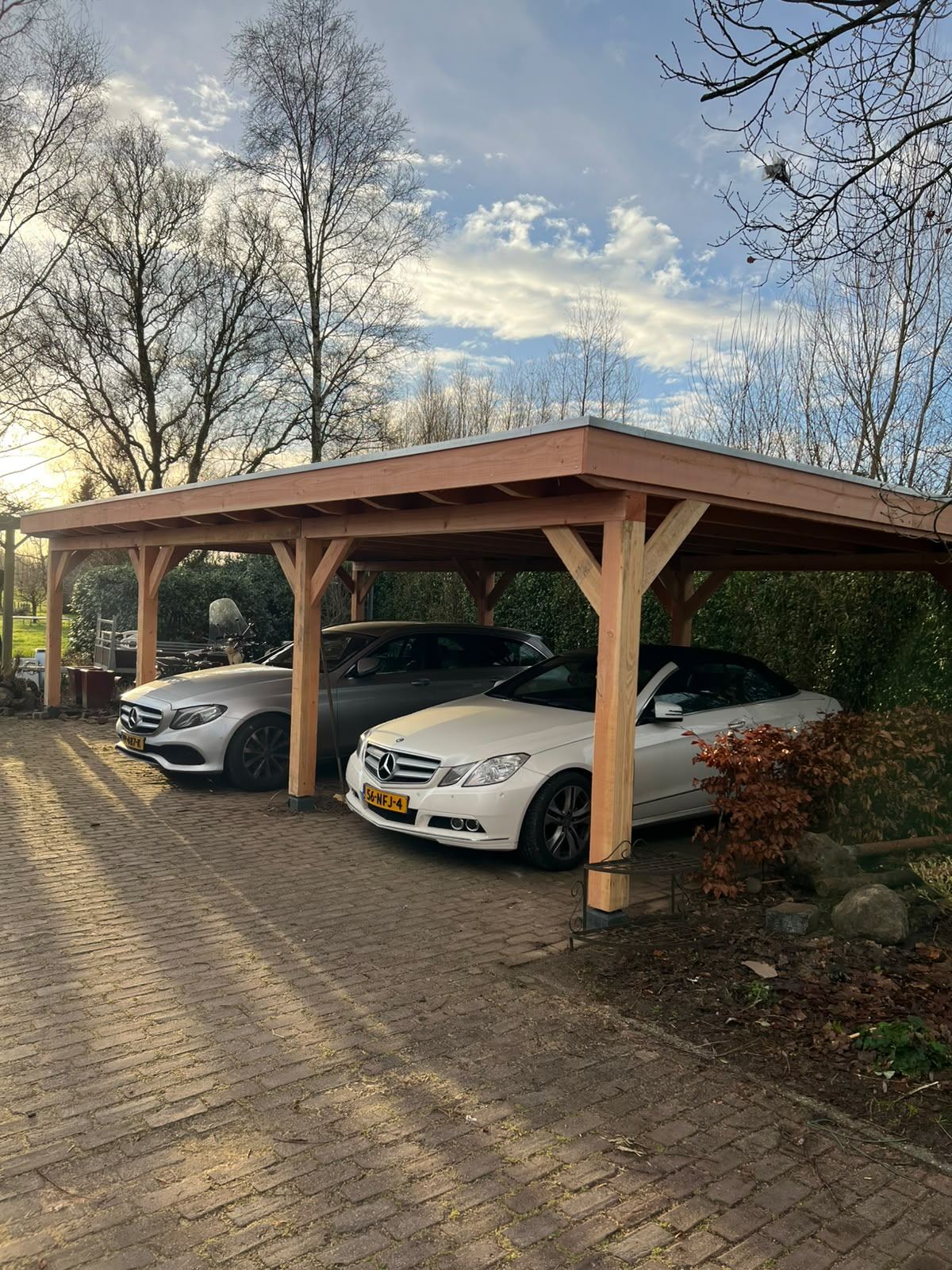 Douglas carport met plat dak waaronder twee auto's staan geparkeerd