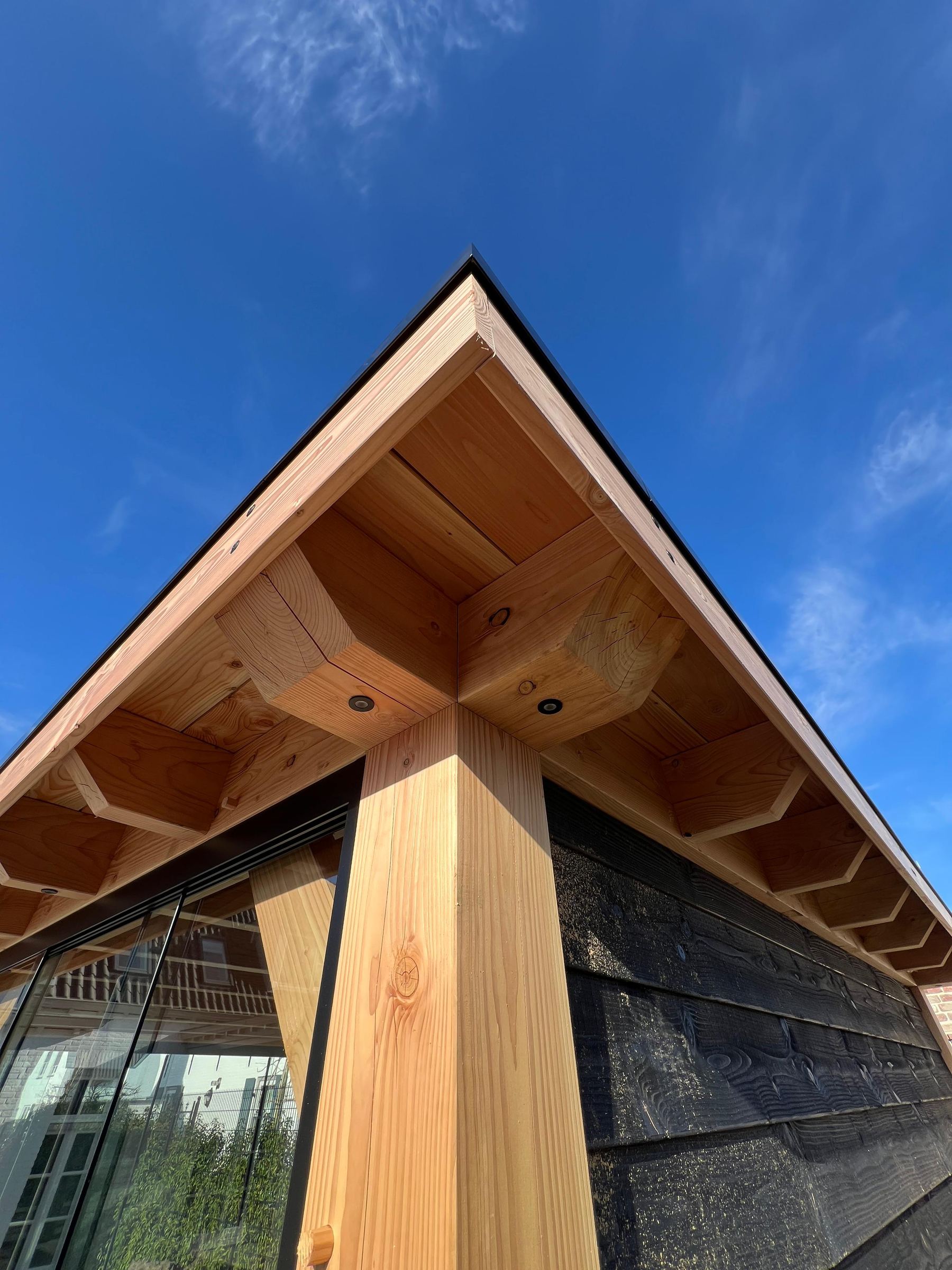 Nok van een houten kap met zichtbare verbinding tegen een blauwe lucht
