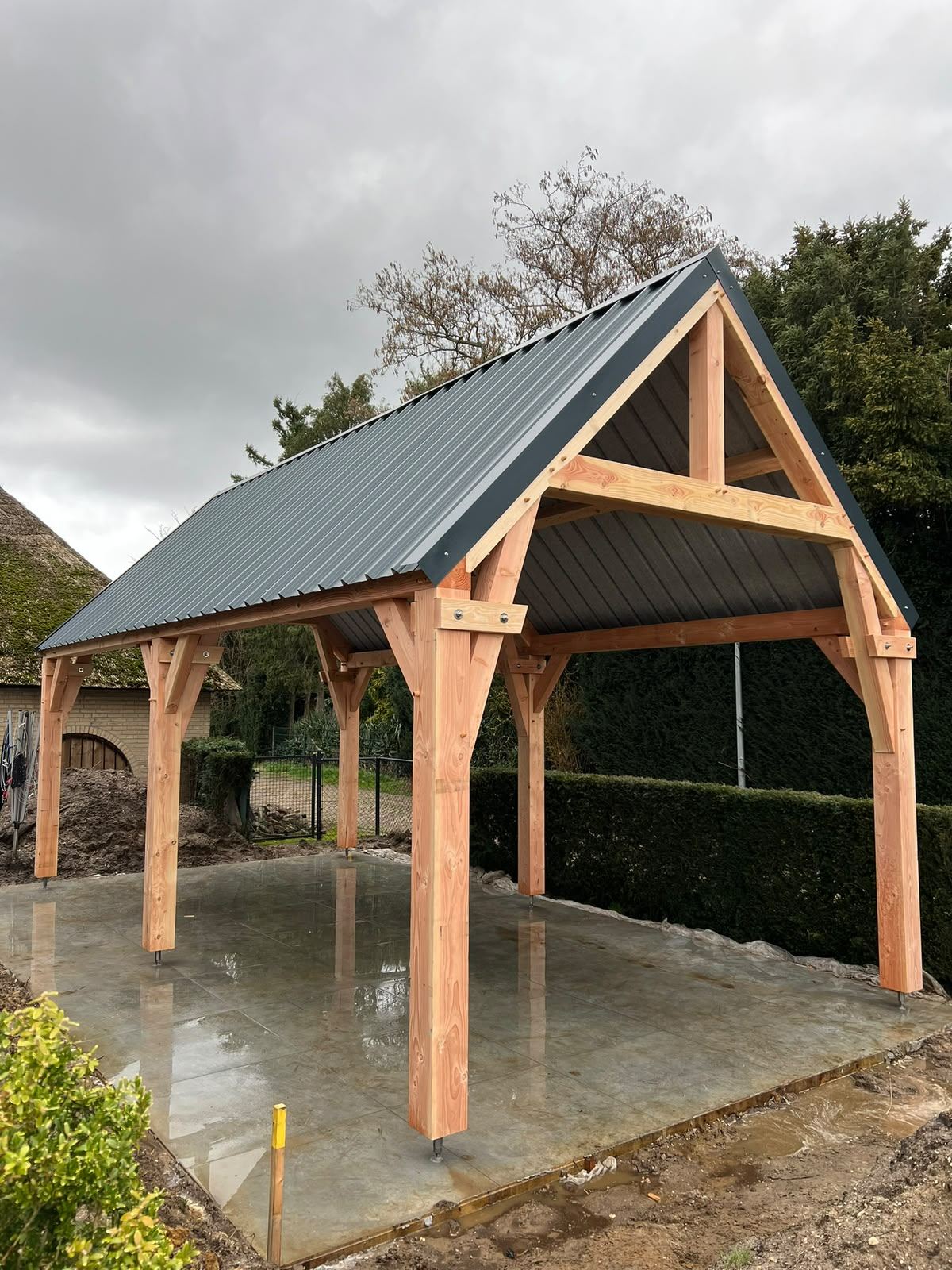 Houten spantconstructie met stalen dakplaten boven een betonvloer